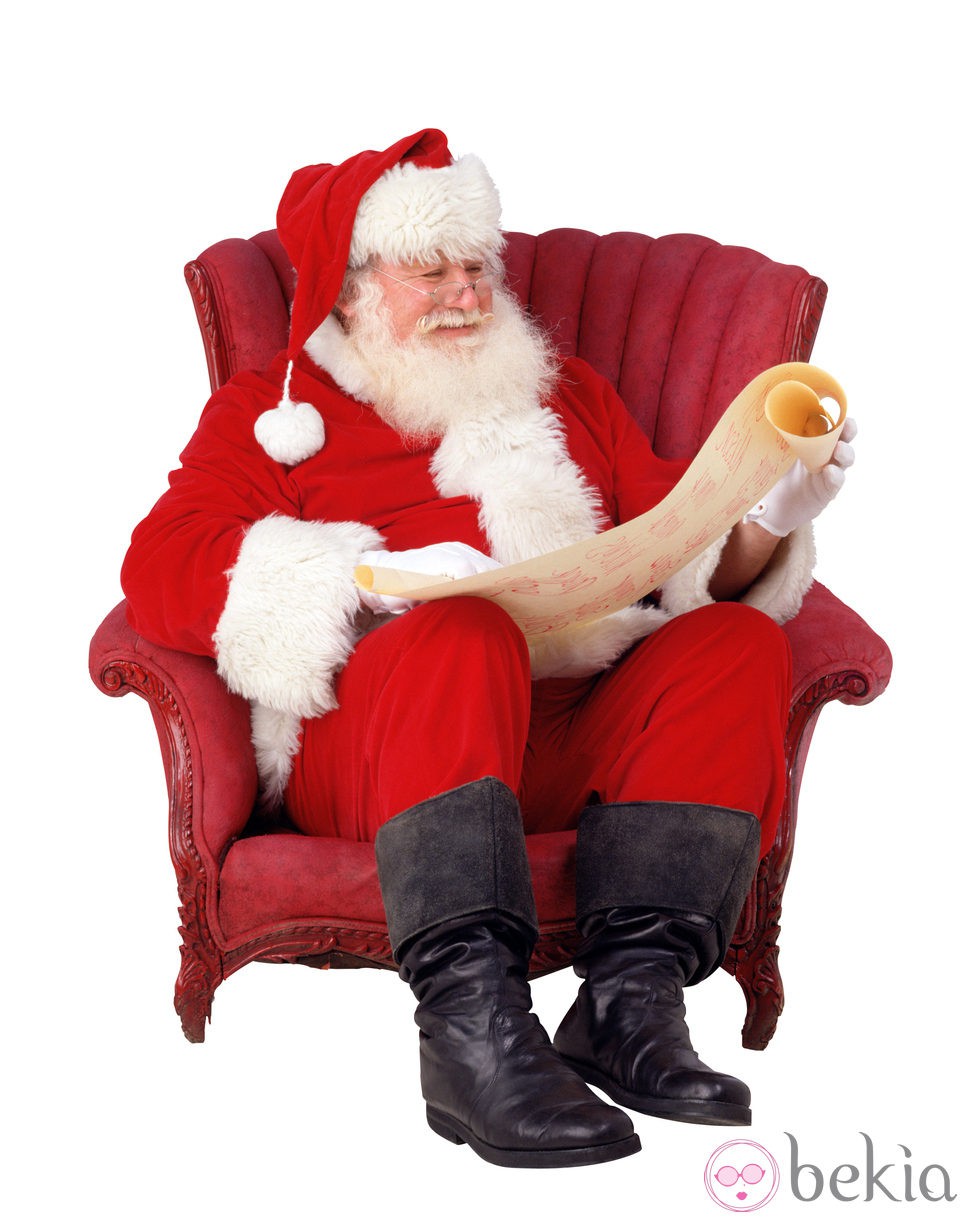 Papá Noel lee la carta de los regalos sentado en un sillón